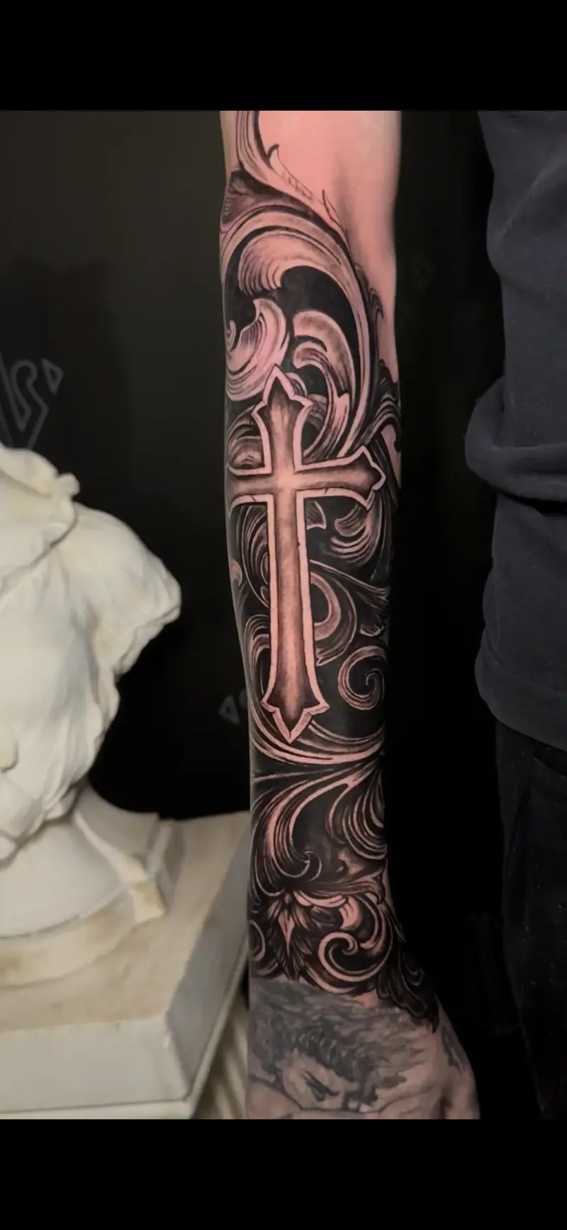 Tatuaje blackwork de cruz con ornamentos en el antebrazo