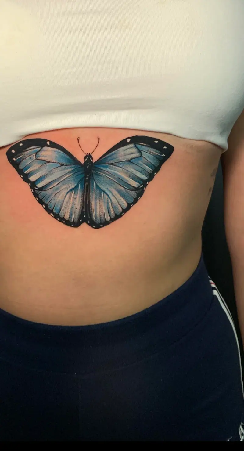 Tatuaje de realismo a color de una mariposa azul