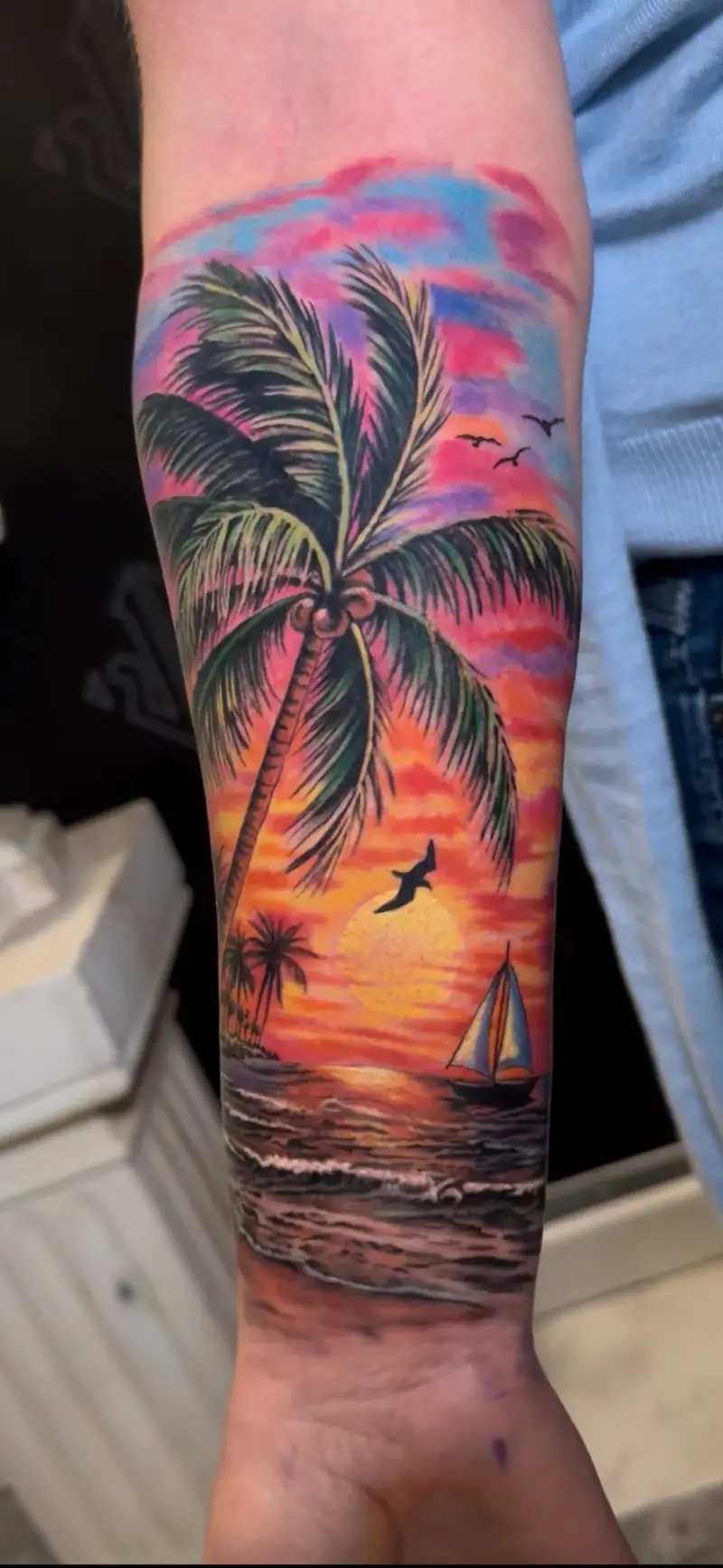 Tatuaje de realismo a color de playa tropical con palmera y velero