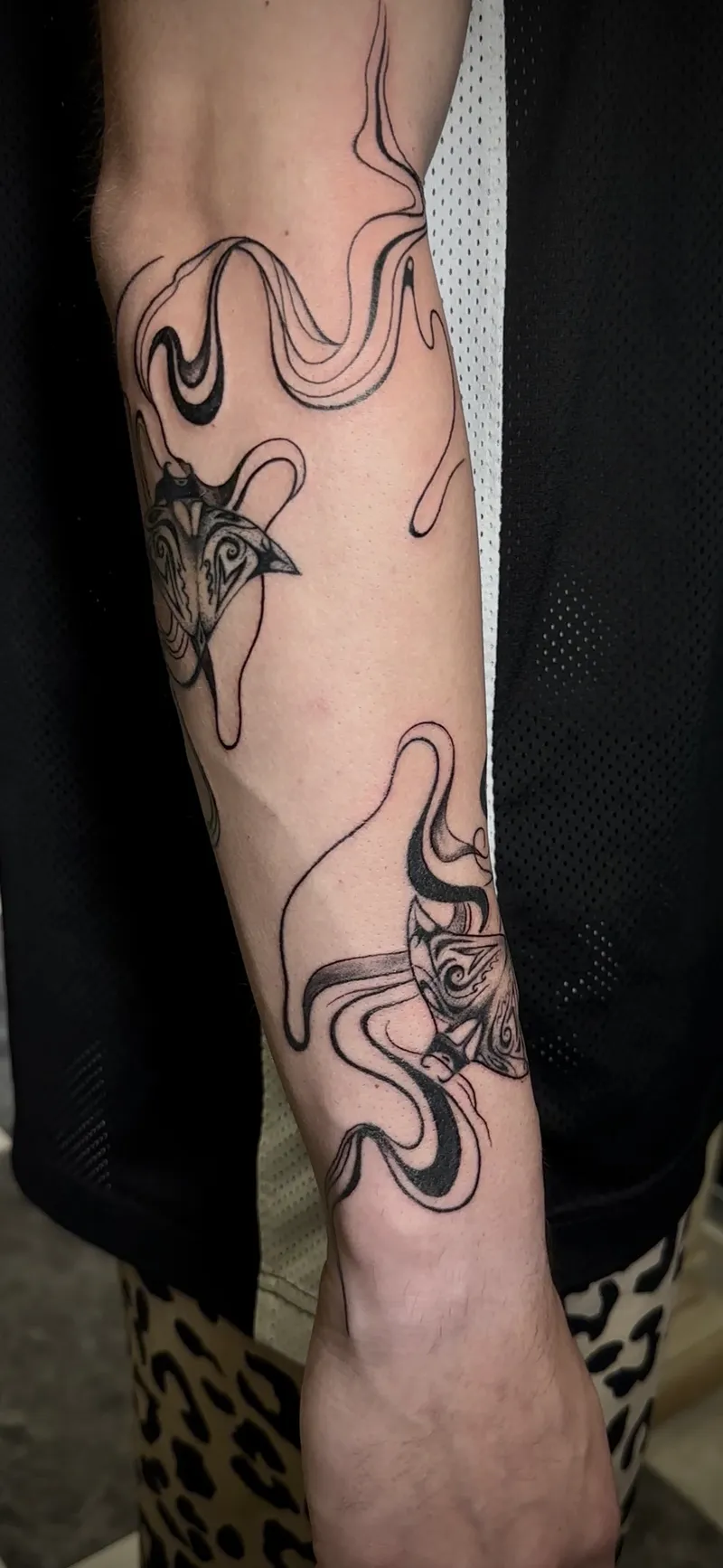 Tatuaje de línea fina abstracta con formas fluidas y geométricas en el brazo