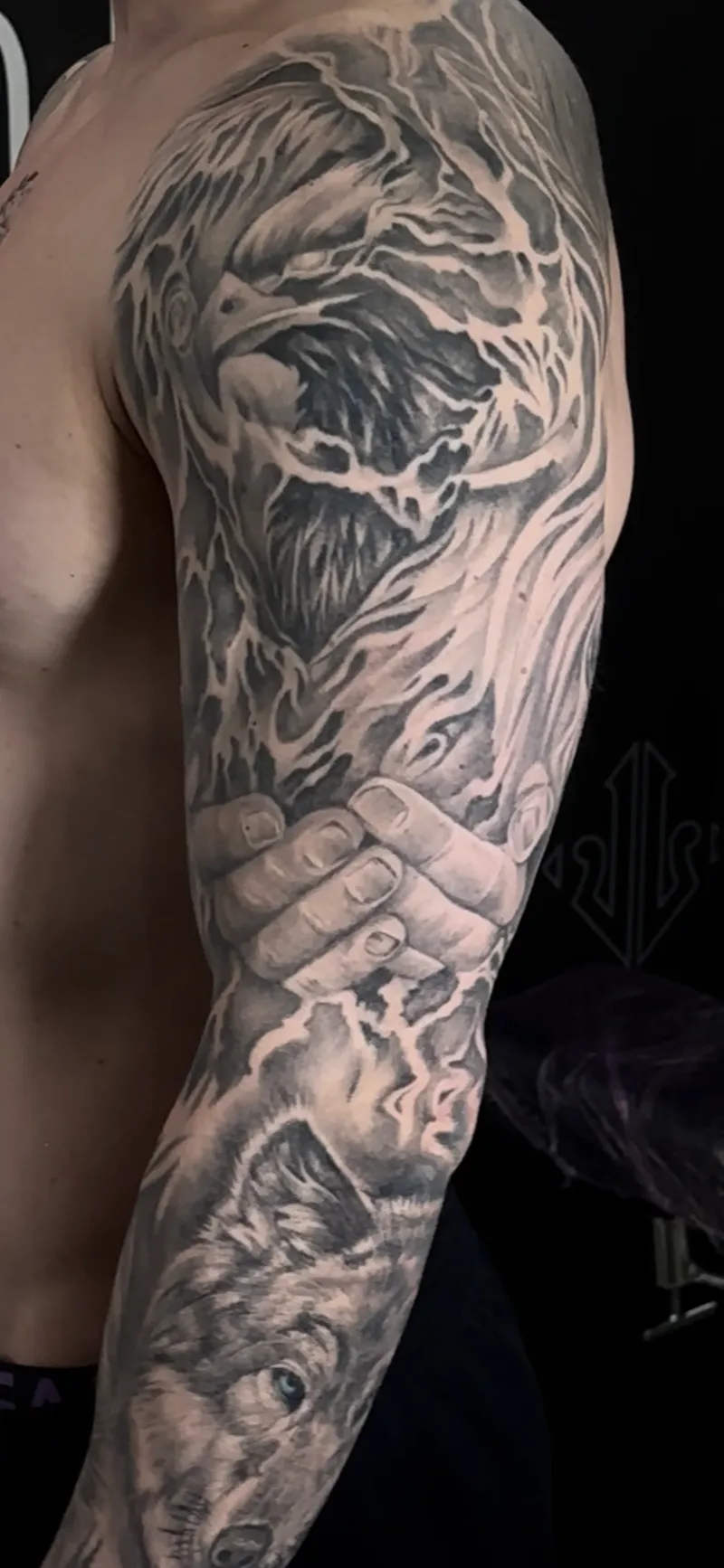 Tatuaje curado en negro y gris en manga completa con fénix, manos y lobo